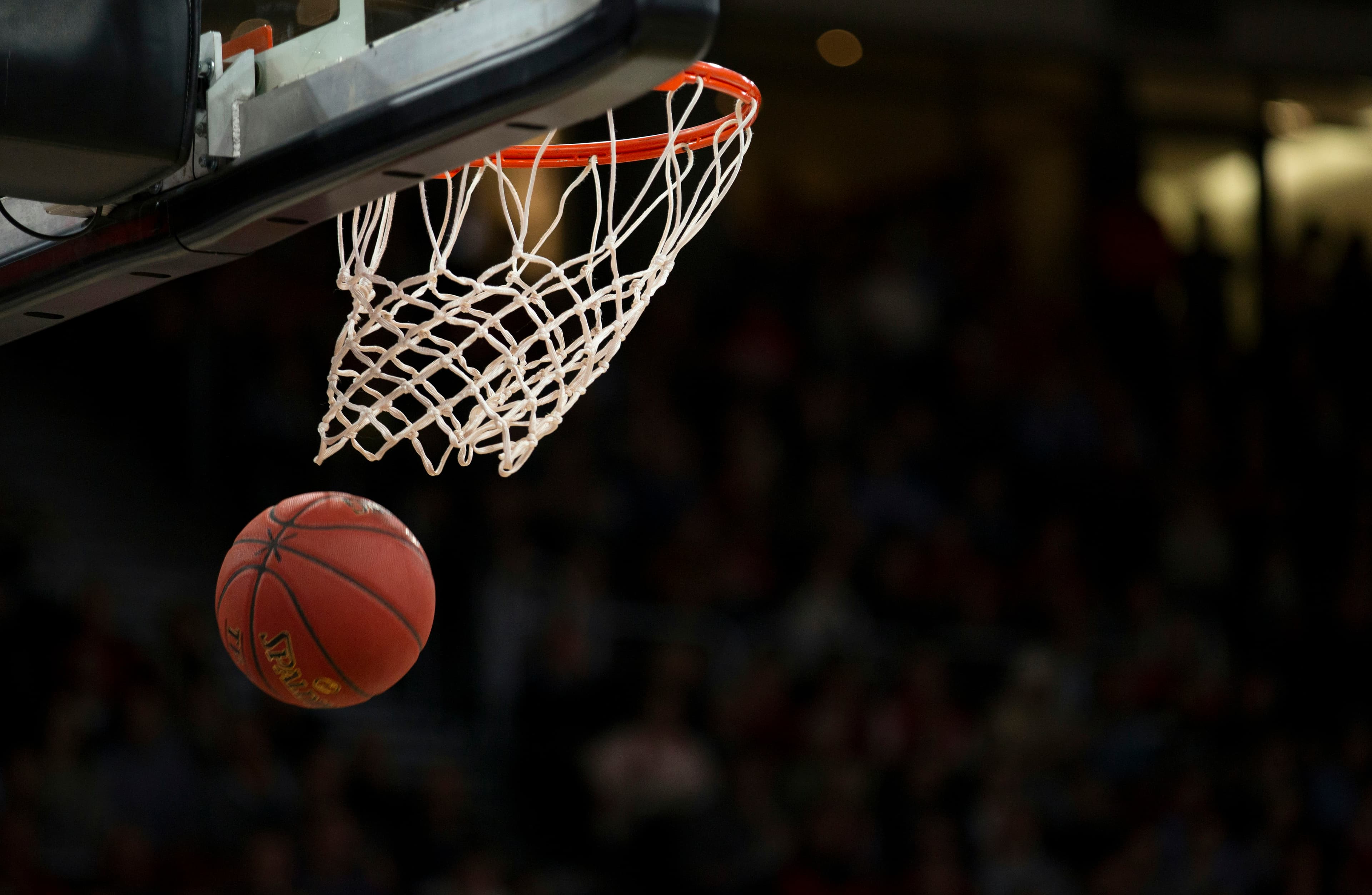 Basketball dropping through the net under stadium lights